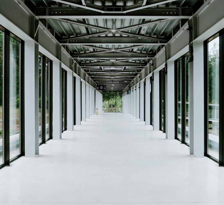 White hallway with glass doors and metal ceiling in a modern building